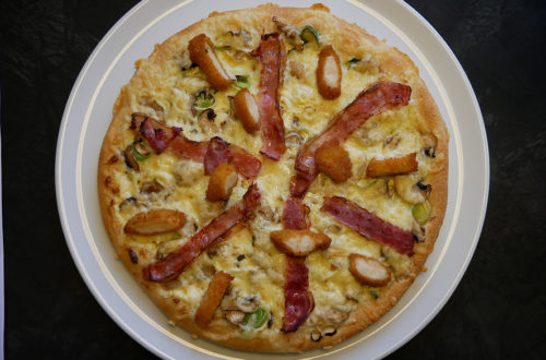 Hallo Pizza! Pizzasorte nicht-vegan von oben auf weißem Teller